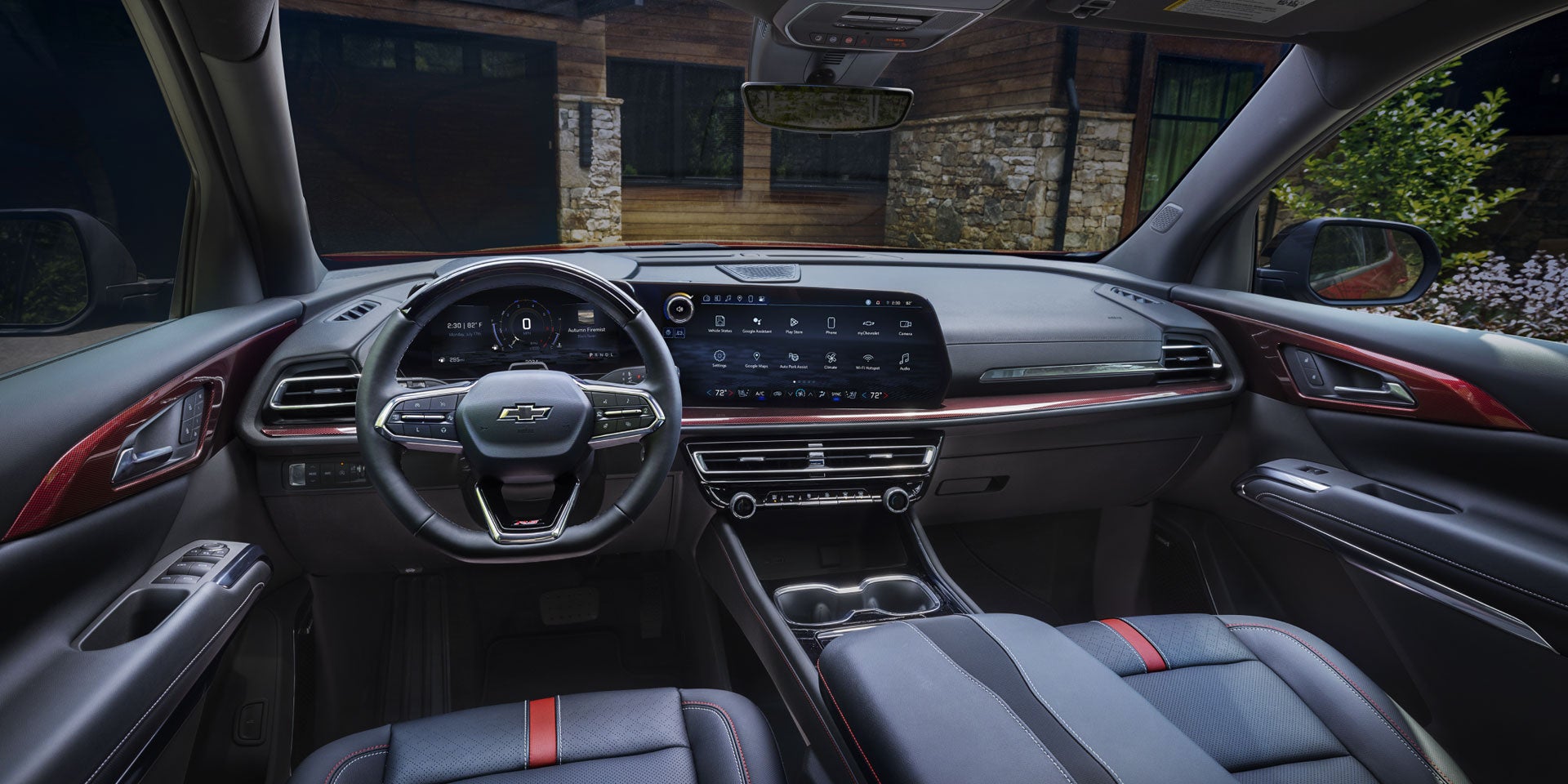 The interior of a vehicle featuring a large digital display for navigation and controls, with red accents.