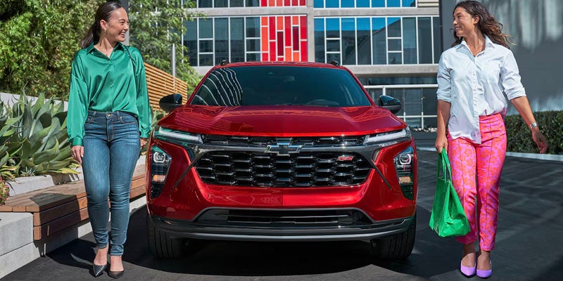two women on the sides of red chevy trax